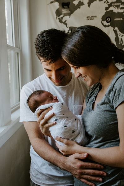女人抱着婴儿在男人身边微笑